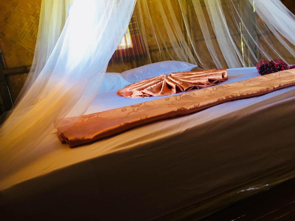 Una cama con mosquitera encima. en Koh Phaluai Beach Bangalow en Ban Ko Nok Taphao