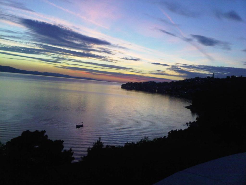 a view of a lake at sunset with a boat on it at Apartments Vile Holiday in Živogošće