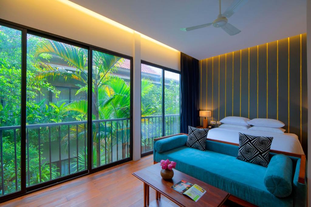 a bedroom with a blue couch and large windows at Silver Urban in Siem Reap