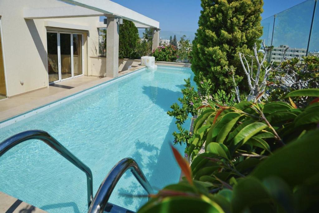 a swimming pool with blue water and green plants at Huge Penthouse with Private Pool in Paphos City