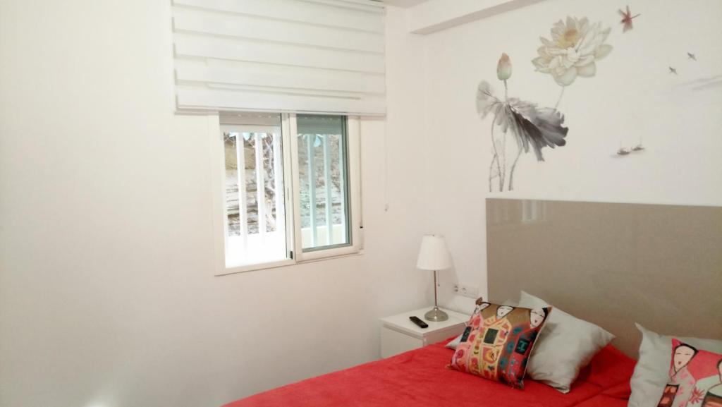 Costa Adeje Mareverde في أديخي: غرفة نوم بسرير احمر ونافذة