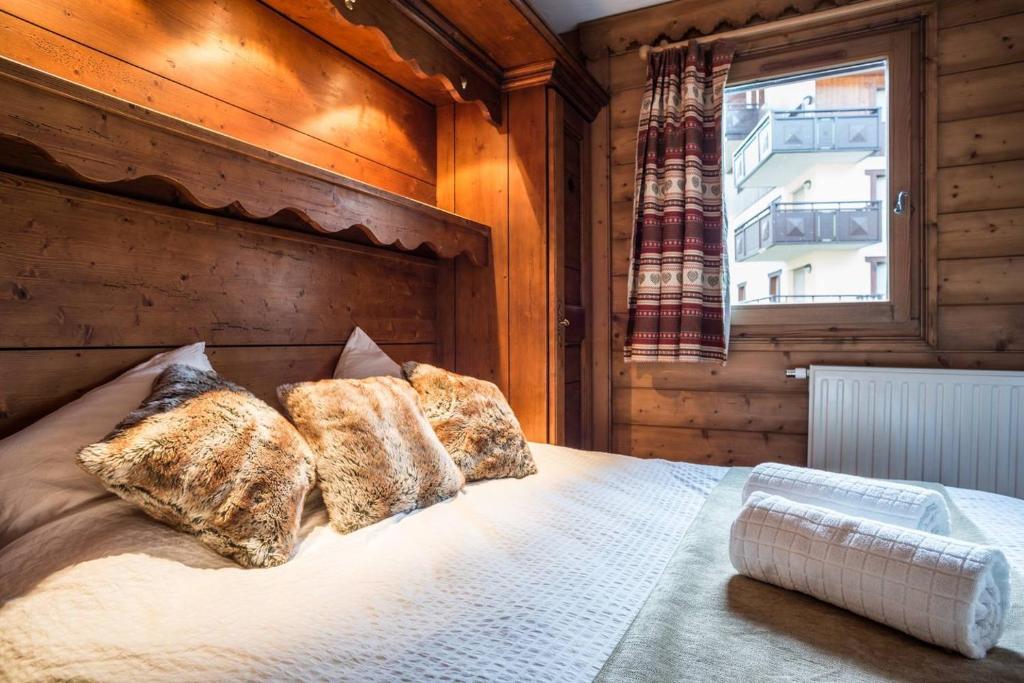 a bedroom with a bed with pillows and a window at La Ginabelle Chamonix in Chamonix-Mont-Blanc