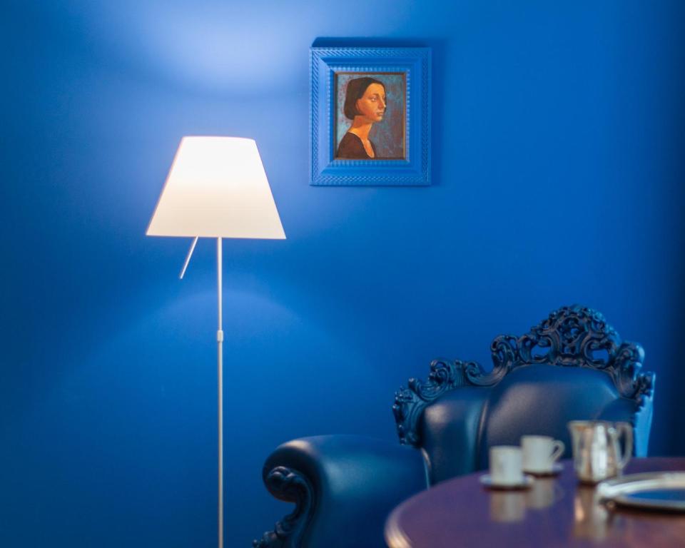 ein blaues Zimmer mit einem Tisch und einer Lampe in der Unterkunft ViandanteHome, Luxury Rooms in Triest