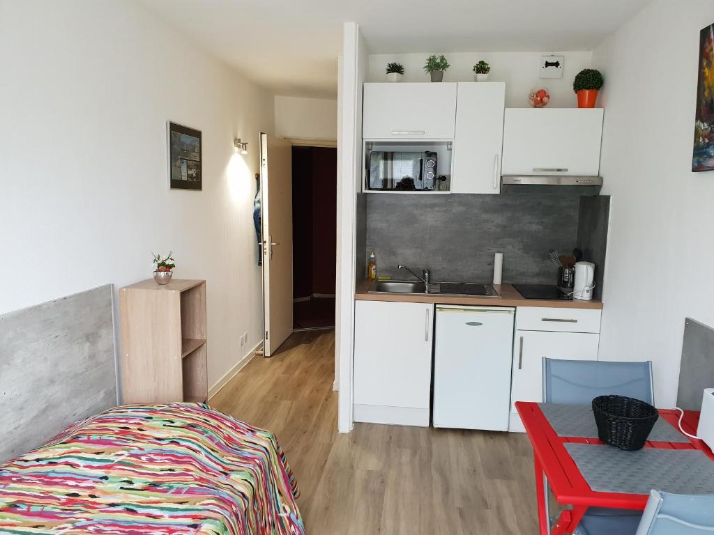 a small kitchen with white cabinets and a red table at Studio port de plaisance in Les Sables-d'Olonne