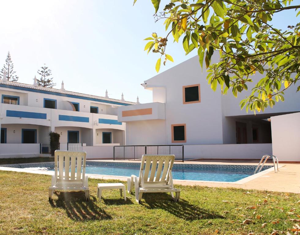 duas cadeiras em frente a um edifício com piscina em Oasis Beach Apartments na Praia da Luz