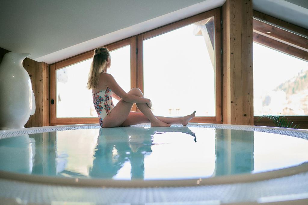 a woman sitting on the edge of a swimming pool at Hôtel Avancher in Val-d'Isère
