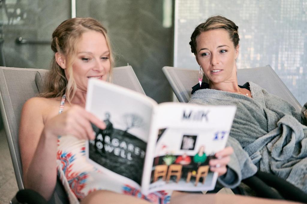 two women sitting on a couch reading a book at Hôtel Avancher in Val-d'Isère