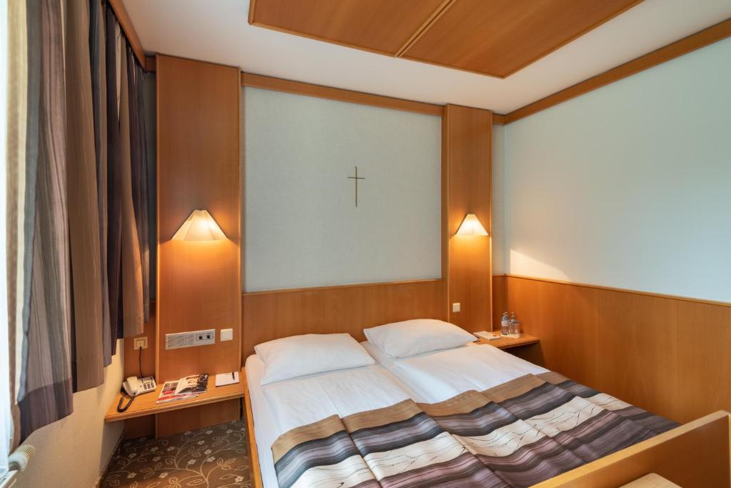 a bedroom with a bed with a cross on the wall at Hotel Gasthof Seeland in Sankt Pölten