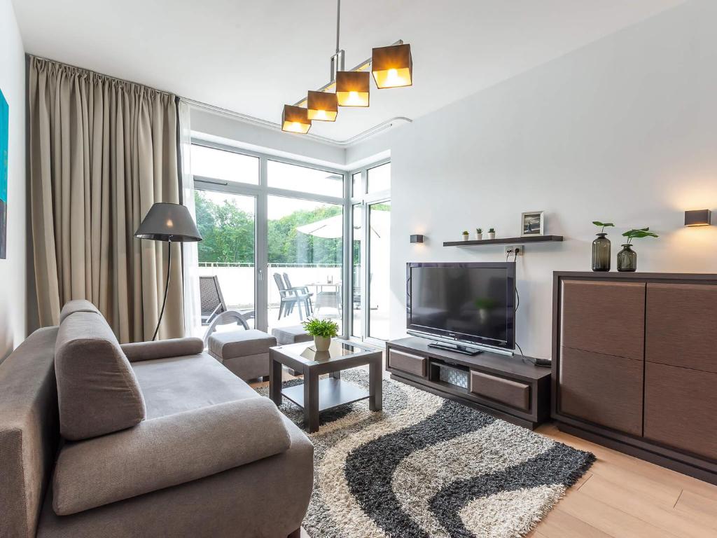 a living room with a couch and a television at VacationClub - Diune Resort Apartment B110 in Kołobrzeg