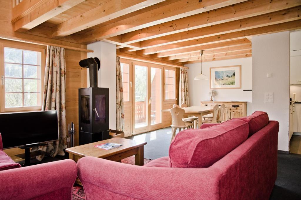 sala de estar con 2 sofás rojos y TV en Apartment Eiger - GRIWA RENT AG, en Grindelwald