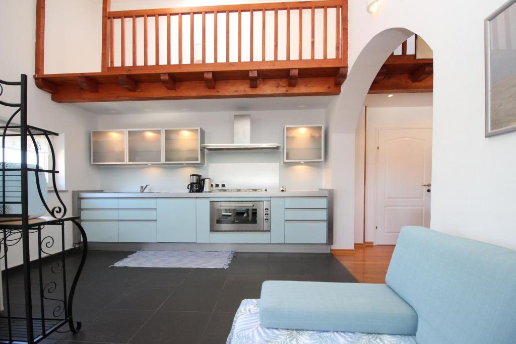 a kitchen with white cabinets and a blue chair at Apartments Tironi in Baška