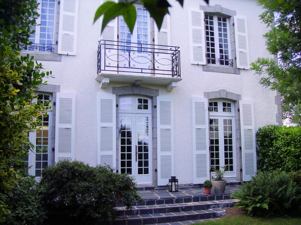 een wit huis met witte ramen en een balkon bij Au Fil de l'Aulne in Châteauneuf-du-Faou