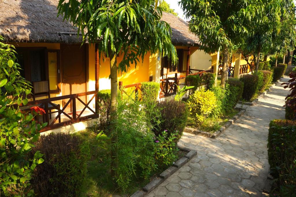 a yellow house with trees and a path next to it at Mr. B's Place in Bhurkīā