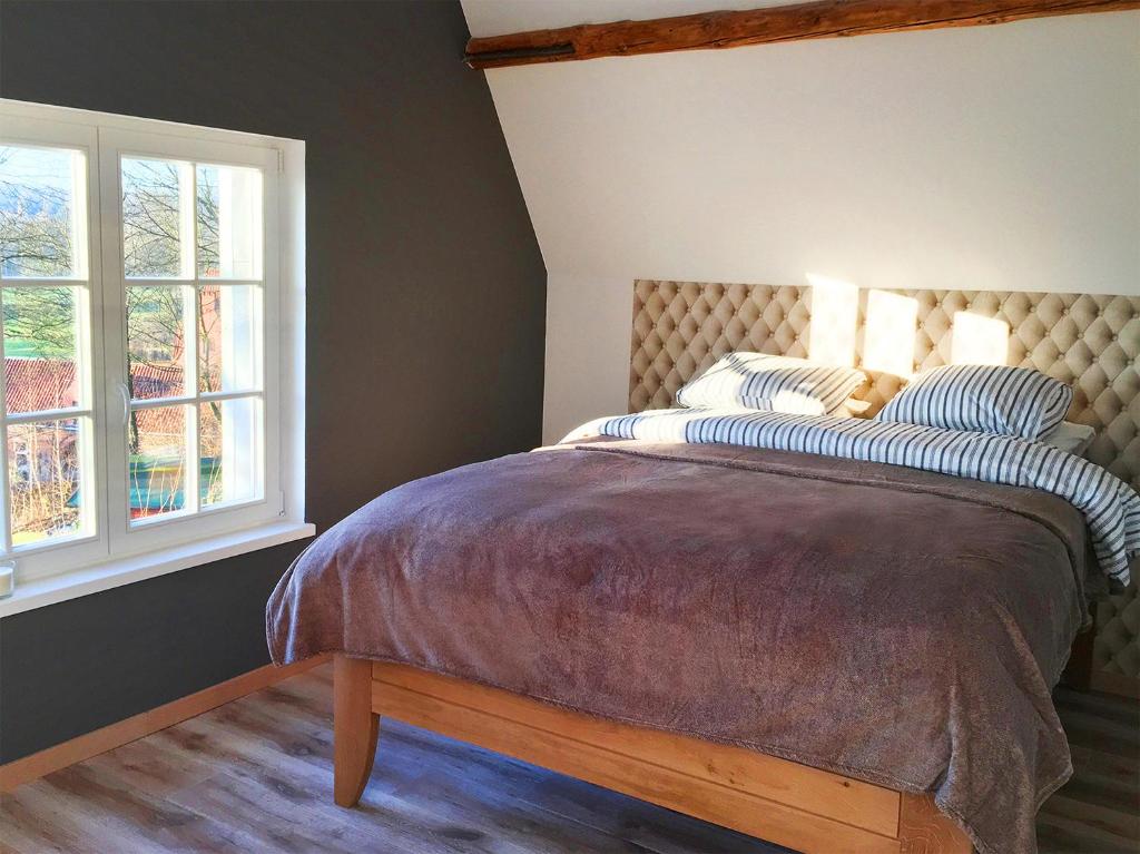 a bedroom with a bed and two windows at Wengé Lodge in Chaumont-Gistoux