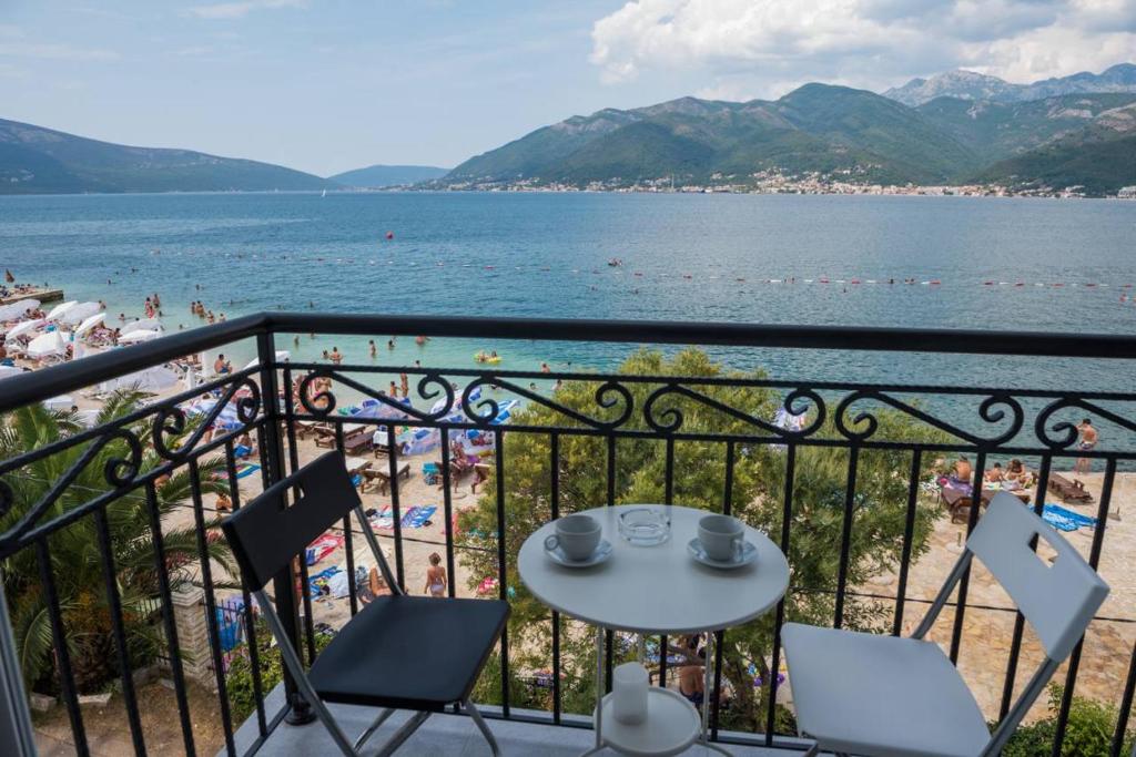 a balcony with a table and chairs and a beach at " Tiamat " apartmani in Tivat