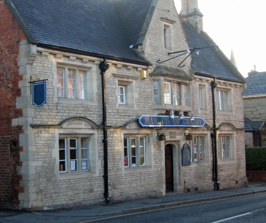 um velho edifício de tijolos com um sinal azul em Marquis of Granby em Sleaford
