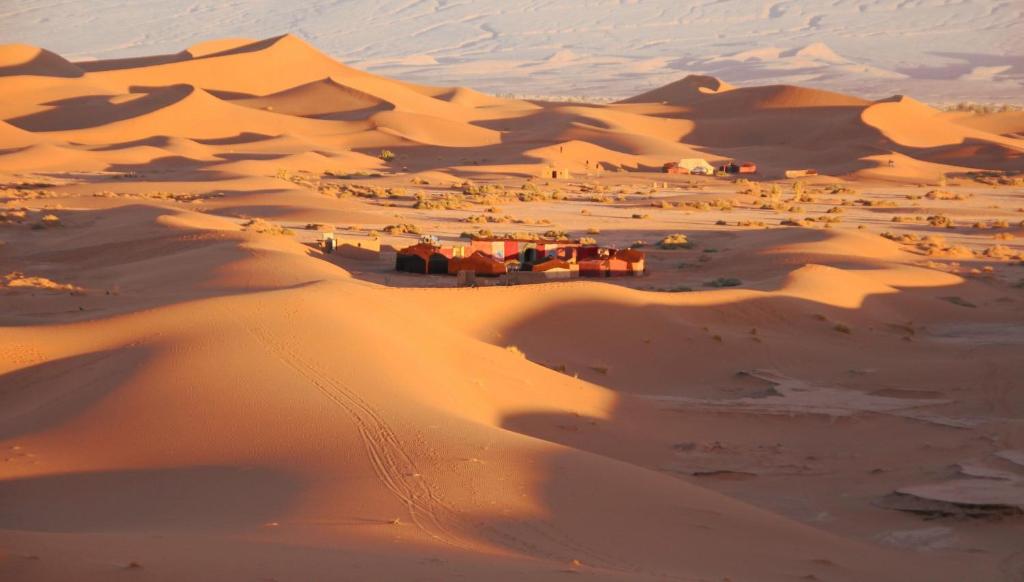 Un desierto con un grupo de casas en la arena en Camp Desert Bivouac Chegaga, en El Gouera