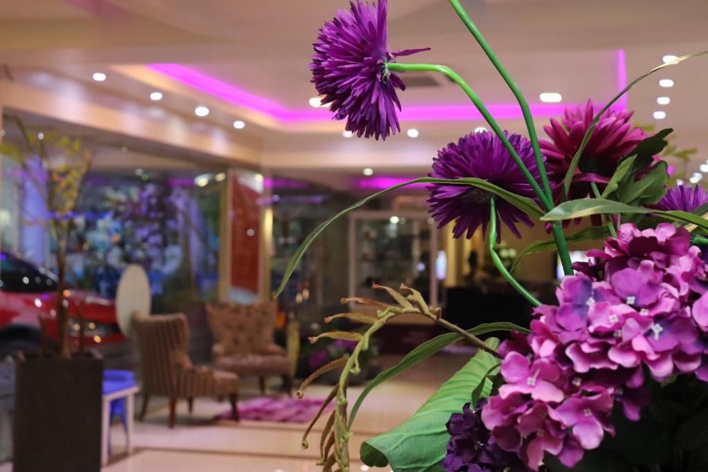 un jarrón lleno de flores púrpuras en el vestíbulo en Luxsur, en Encarnación