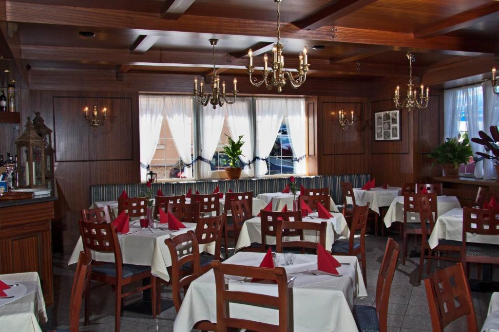 a dining room with white tables and chairs and windows at Hotel Albergo Mamma Rosa in Wunsiedel