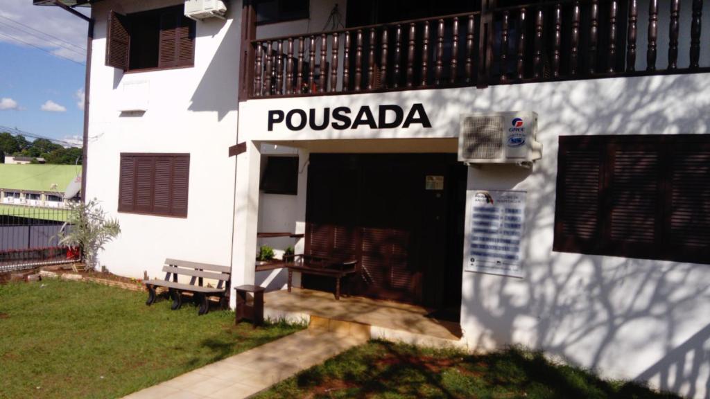 ein weißes Gebäude mit einer Bank davor in der Unterkunft Pousada Arco Íris in Tabapira