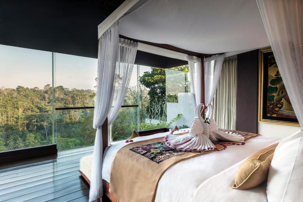 a bedroom with a bed with a large window at Ayuterra Resort in Ubud