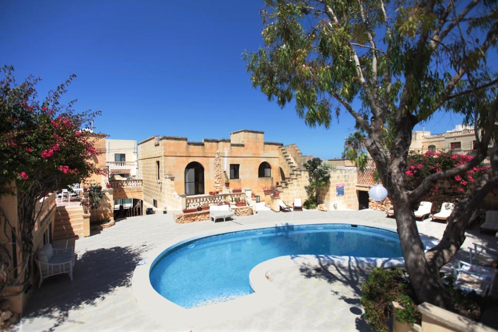 a pool in front of a building with a tree at Gozo Holiday Apartmen - 2 Bedroom Villa with Shared Pool in Xagħra