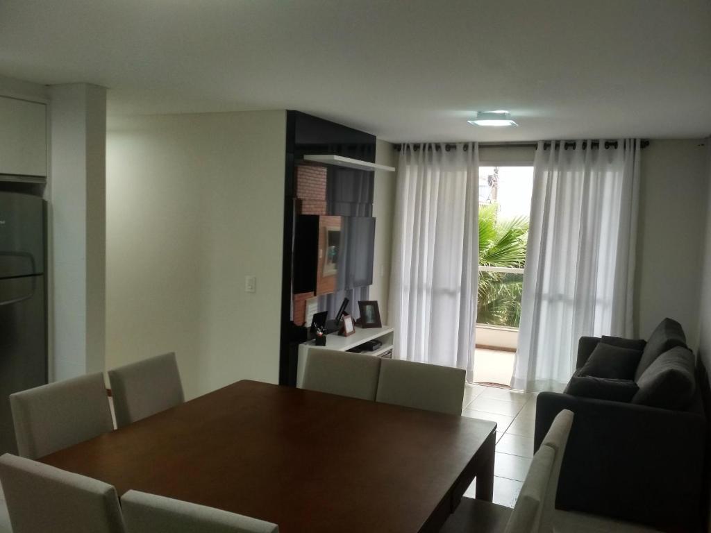 comedor con mesa, sillas y ventana en Mahalo Happy Apartment, en Florianópolis