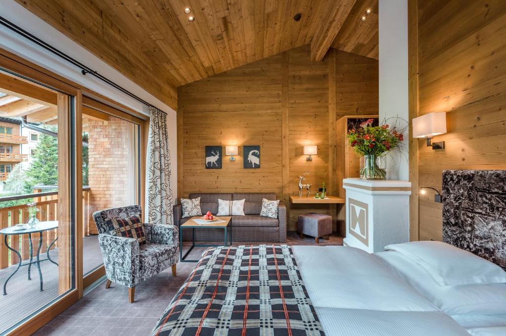 a bedroom with a bed and a living room at Hotel Auenhof in Lech am Arlberg