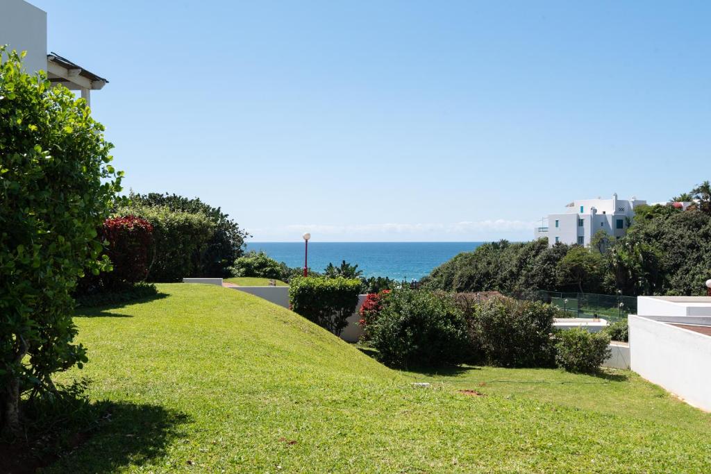 a lawn with the ocean in the background at Santorini Kallisti 7 (Family Only) in Ballito