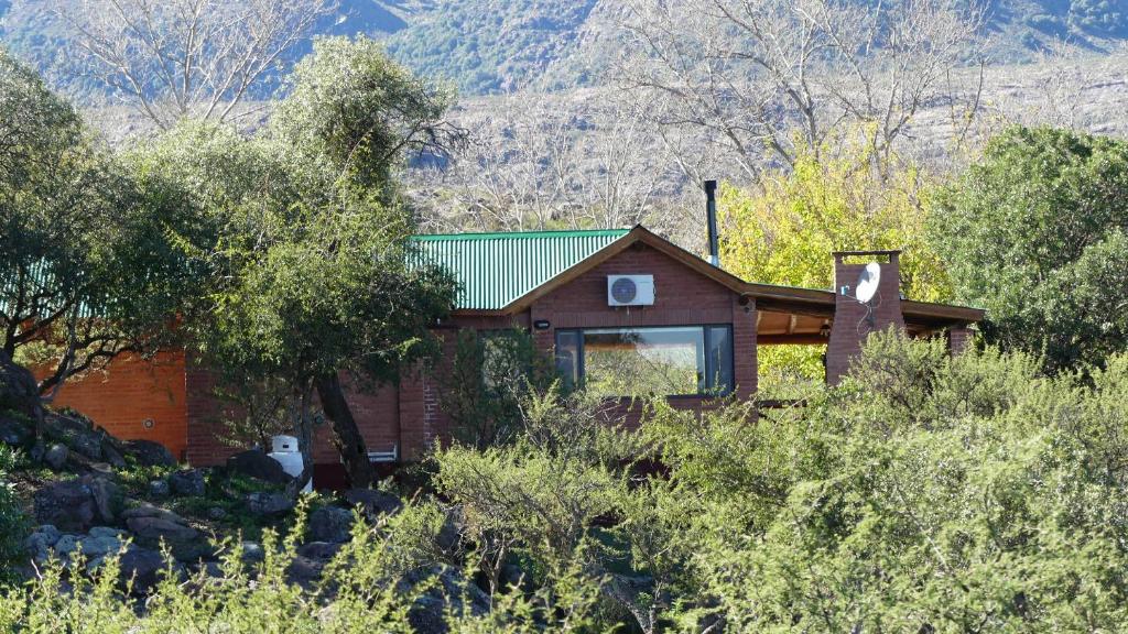 uma casa com um telhado verde numa montanha em Cabañas Pampa em Mina Clavero