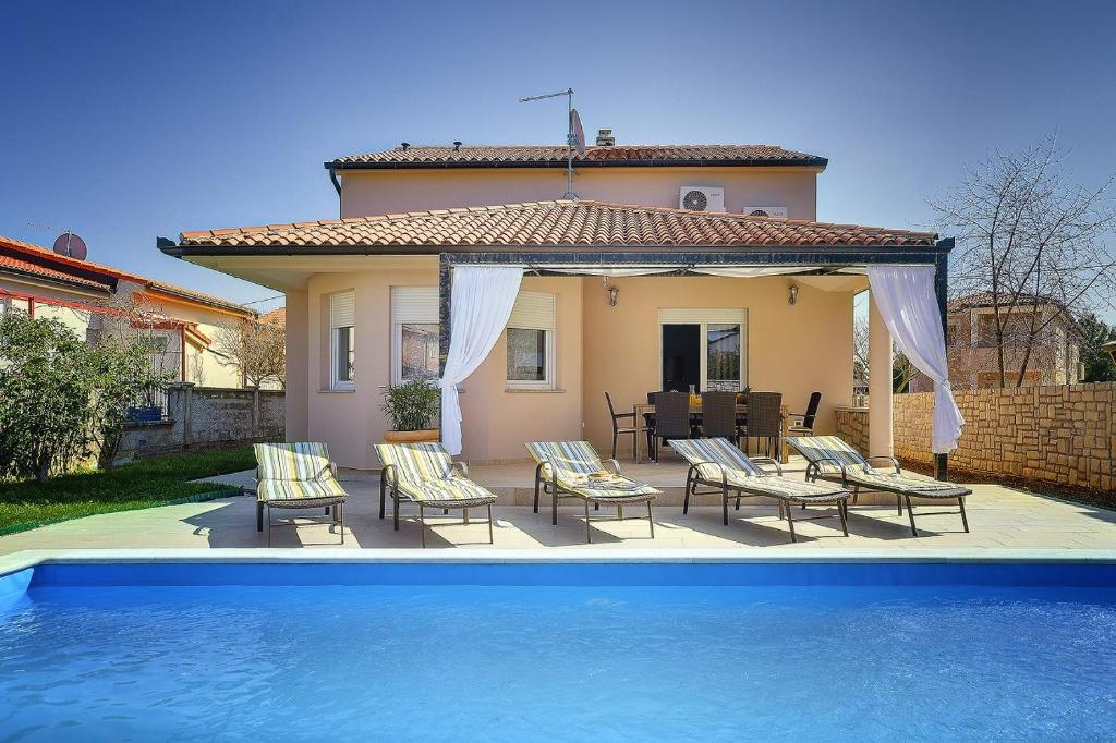 a house with a patio with chairs and a pool at Villa Rudy in Štinjan