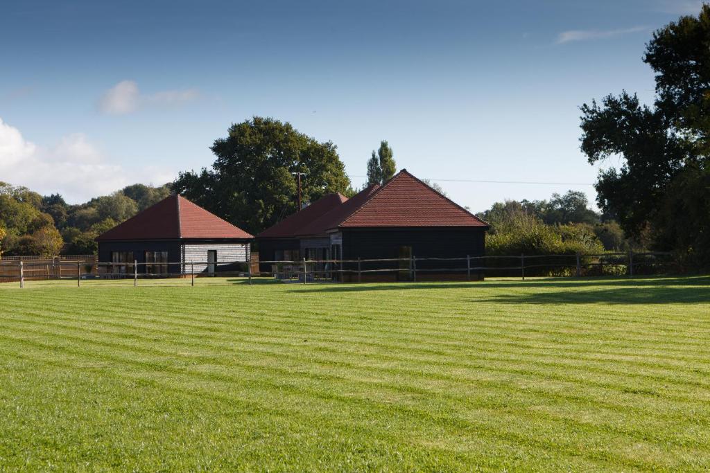 a large grass field with two buildings in the background at The Old Flower Field in Hurstpierpoint