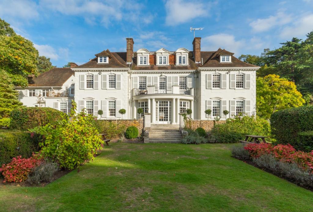 an exterior view of a large white house with a yard at Gorse Hill Hotel in Woking