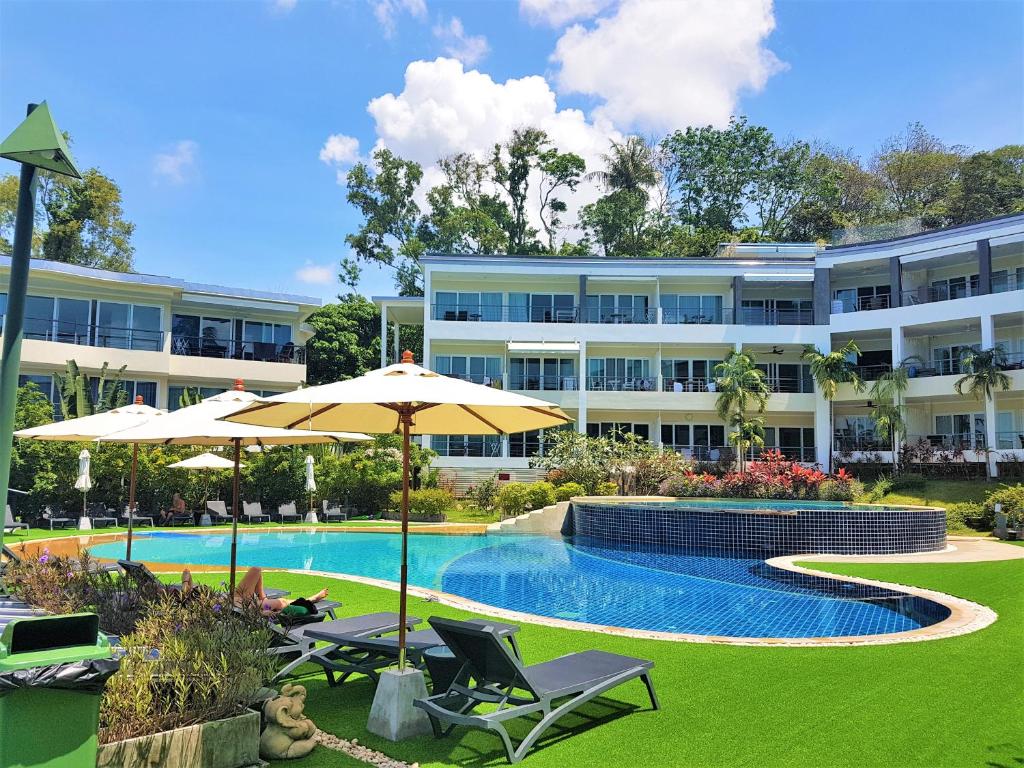 a hotel with a swimming pool and two chairs and an umbrella at KB Apartments Karon Beach by PHR in Karon Beach