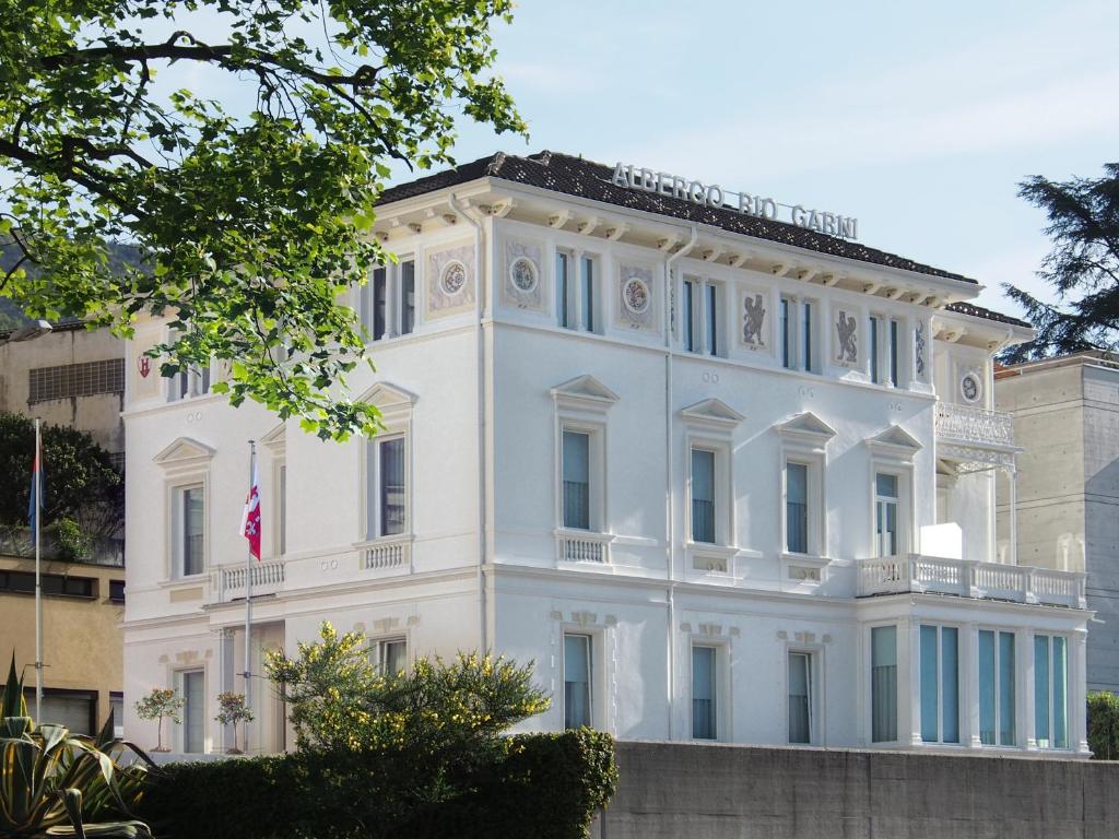 a white house with a flag on it at Hotel Rio Muralto in Locarno