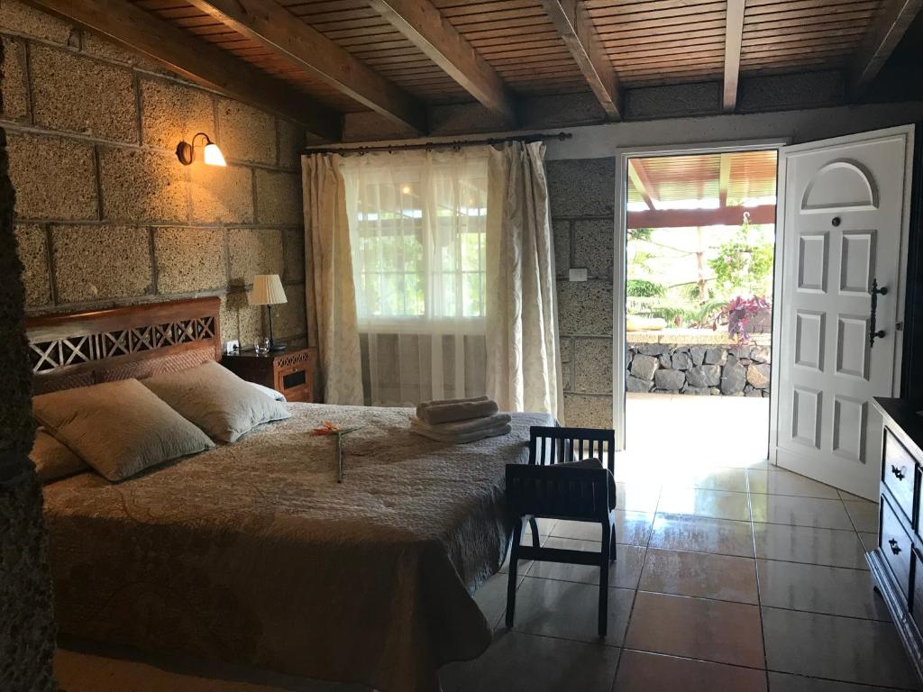 een slaapkamer met een bed, een stoel en een deur bij Finca el Cortijo in San Miguel de Abona