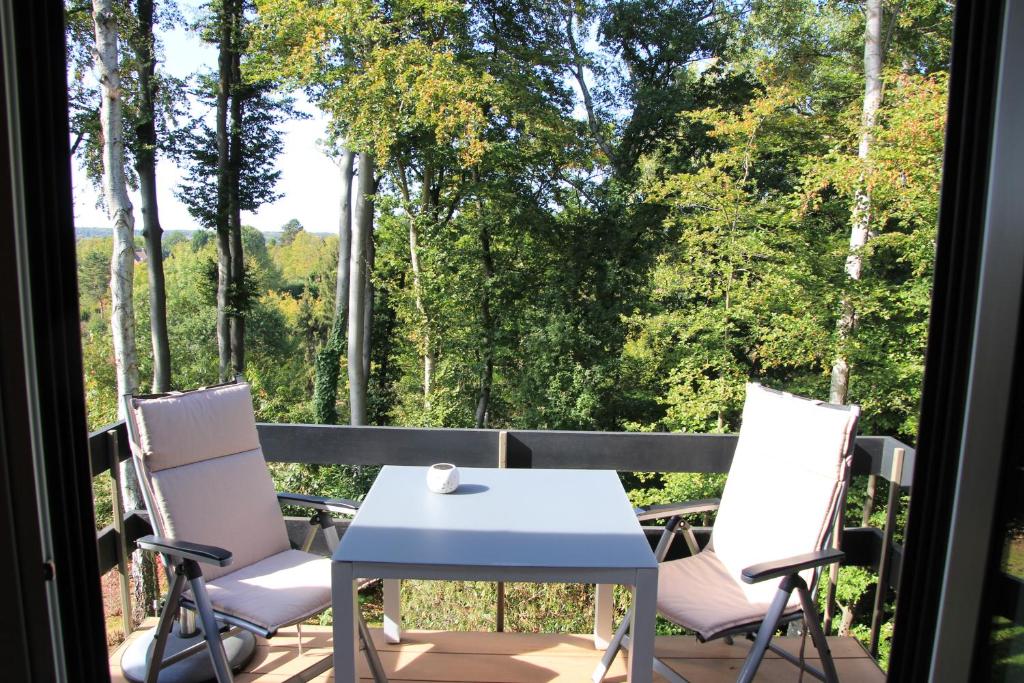 a table and chairs on a balcony with a view of trees at Green Hill Apartment Overijse in Overijse