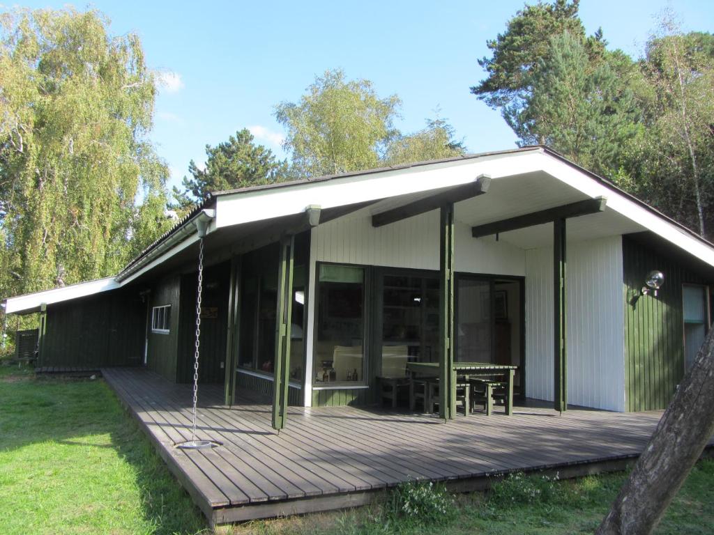 a house with a wooden deck in the yard at Holiday Home Holmehøj in Ebeltoft