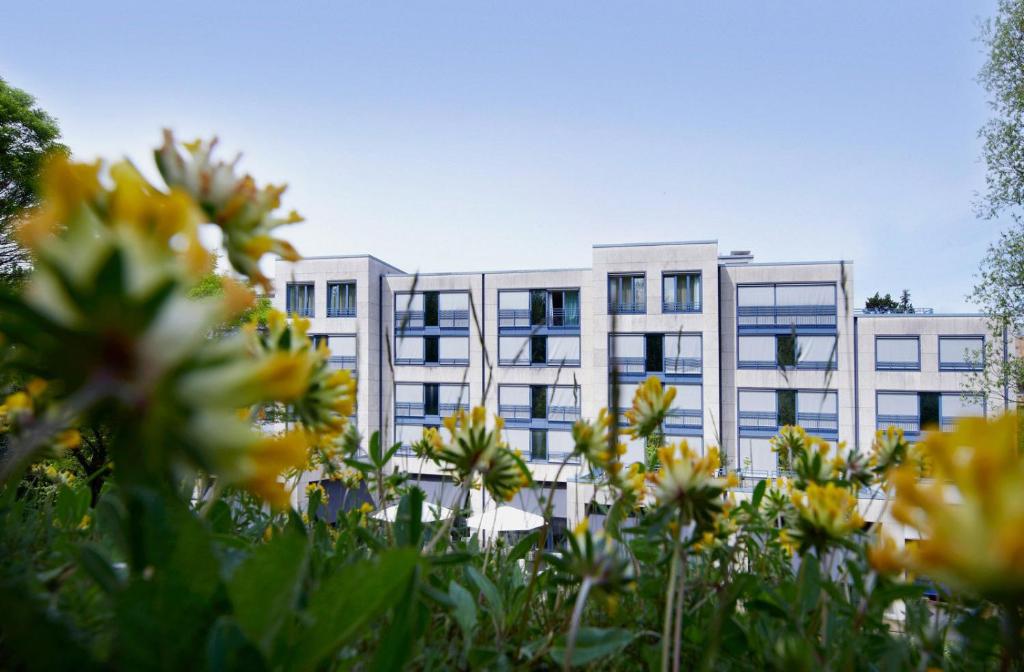 un immeuble de bureaux avec des fleurs jaunes devant lui dans l'établissement Park Hotel Zug, à Zoug