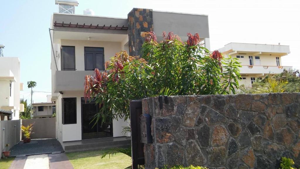 a house with a stone wall in front of it at Happy Villa in Trou aux Biches