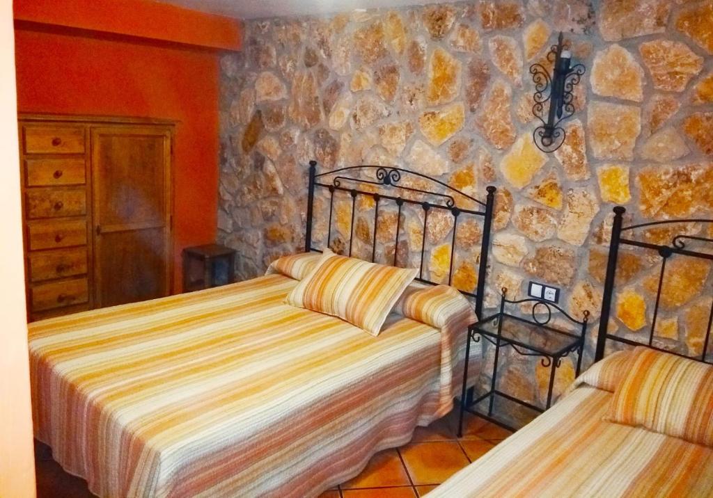 アロヨ・フリオにあるVivienda Los Pineros Arroyo Frioの石壁のベッドルーム1室(ベッド2台付)