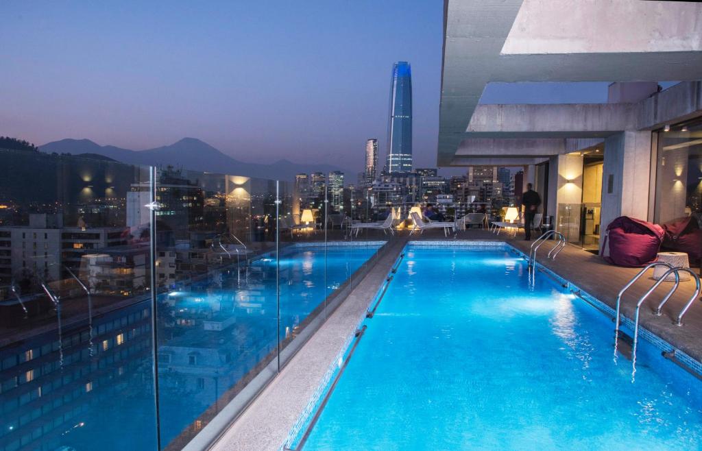 a swimming pool on top of a building with a city at Solace Hotel Santiago in Santiago