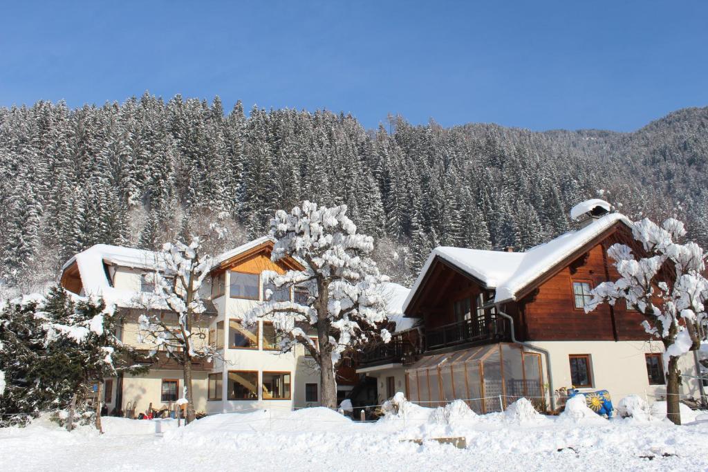 a building covered in snow with trees in the background at Knaller der Reiterbauernhof in Reisach