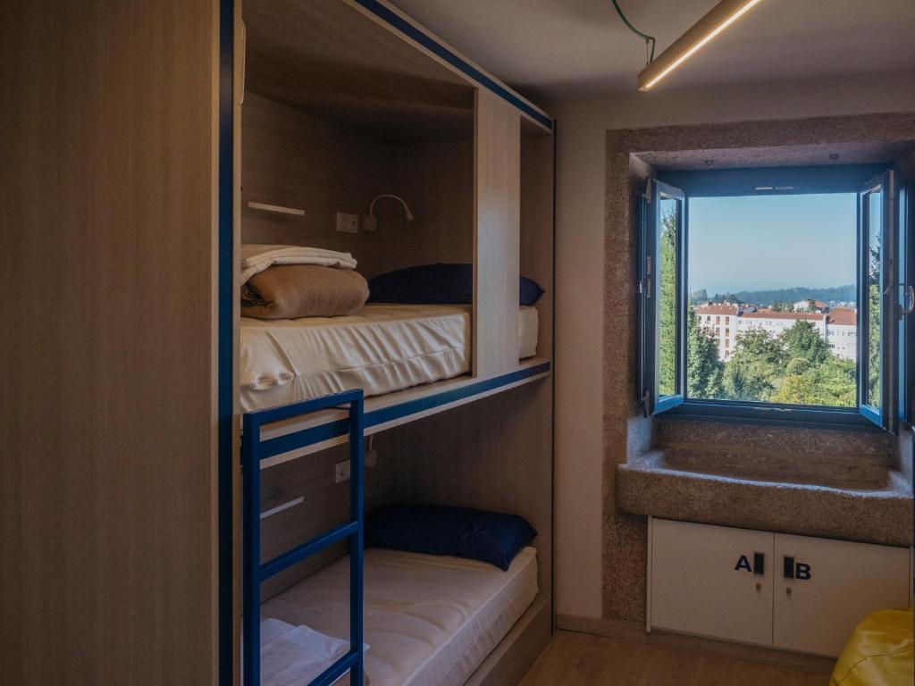 サンティアゴ・デ・コンポステーラにあるSantiago KM-0の二段ベッド2台、窓が備わる小さな客室です。