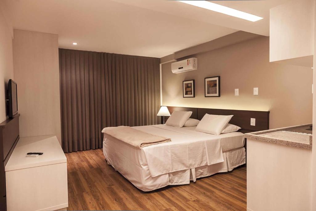 a hotel room with a bed and a television at Atmosfera Hotel in Feira de Santana