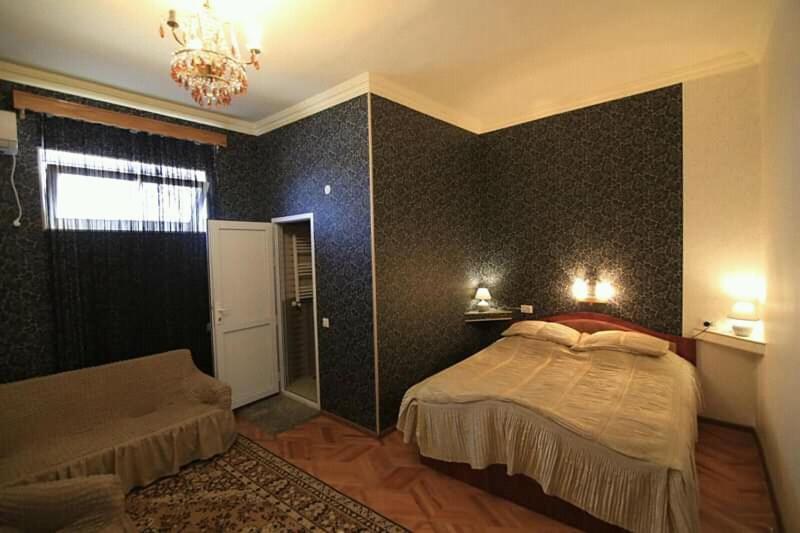 1 dormitorio con cama y lámpara de araña en Guesthouse Raisa, en Kvareli