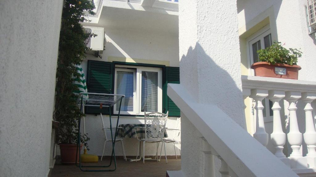 a white building with a balcony with a table and chairs at Studio in Vodice 7524 in Vodice