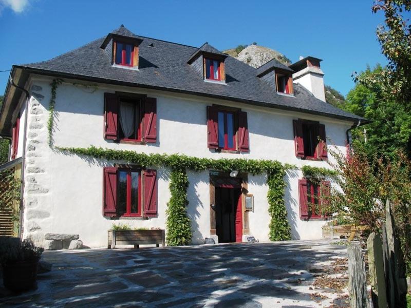 a white house with red shutters and ivy on it at Les gerbes in Arras-en-Lavedan