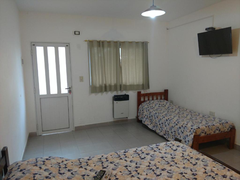 a room with two beds and a television and a door at Los Alamos in Puiggari