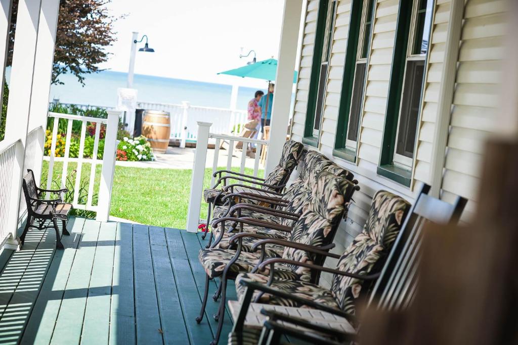 a group of chairs sitting on the porch of a house at The Lakehouse Inn Geneva in Geneva-on-the-Lake